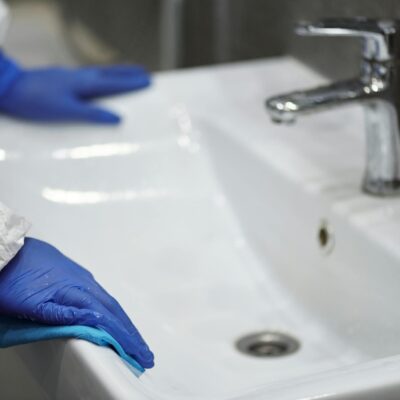 Person in Latex Gloves Cleaning Washbasin